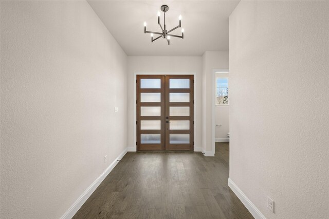 foyer entrance with french doors, dark hardwood / wood-style flooring, and a notable chandelier