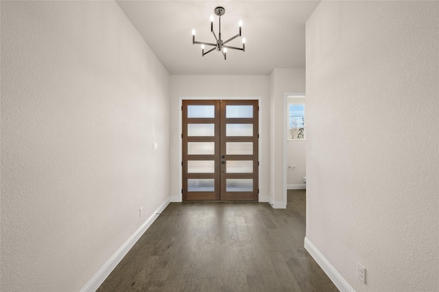 entryway featuring an inviting chandelier, dark wood-type flooring, and french doors