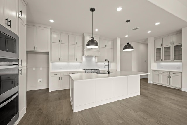 kitchen with sink, an island with sink, and white cabinets