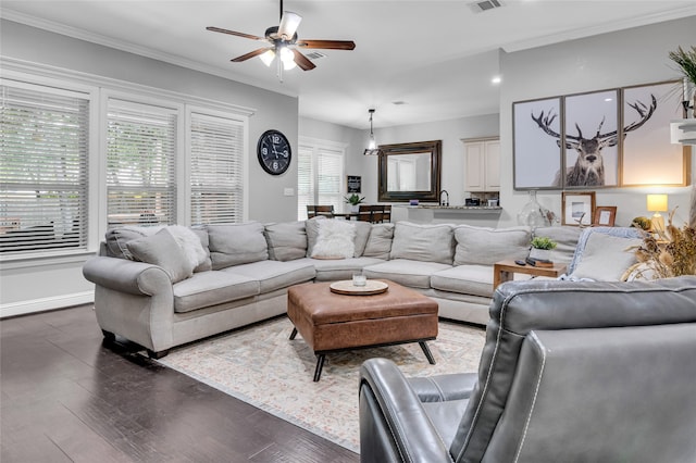 living room with ceiling fan, visible vents, baseboards, dark wood-style floors, and crown molding