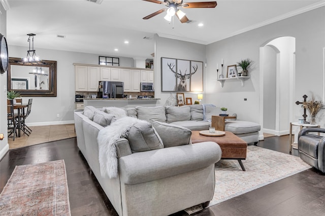 living area featuring arched walkways, dark wood finished floors, crown molding, recessed lighting, and baseboards