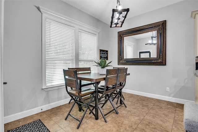 dining area featuring a chandelier, light tile patterned flooring, and baseboards