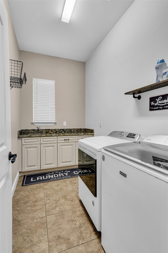 clothes washing area featuring light tile patterned floors, a sink, washing machine and dryer, and cabinet space