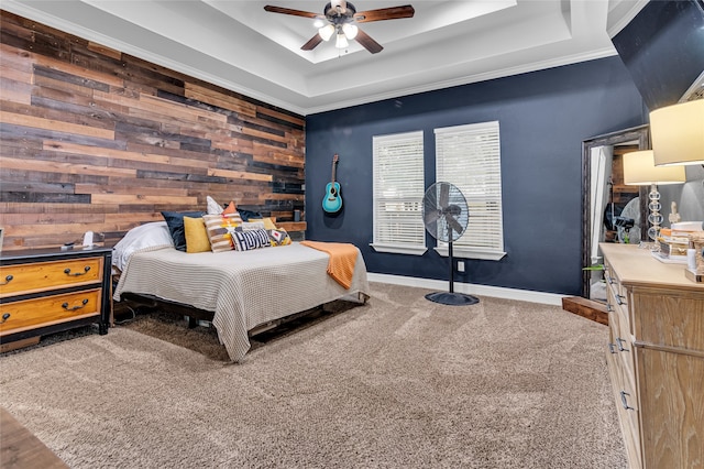 bedroom featuring carpet floors, a raised ceiling, ceiling fan, wooden walls, and baseboards