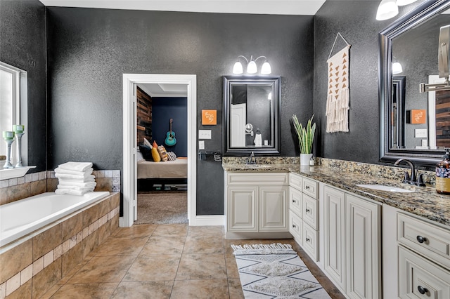 ensuite bathroom with a textured wall, double vanity, a sink, and tile patterned floors