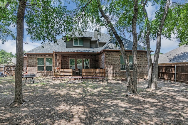 rear view of house featuring brick siding and fence