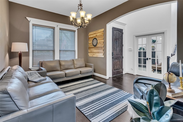 living room featuring baseboards, arched walkways, wood finished floors, french doors, and a notable chandelier