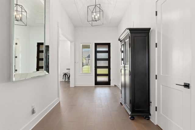 hall with hardwood / wood-style floors and an inviting chandelier