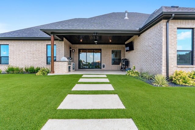 back of house with ceiling fan, a patio area, a lawn, and exterior kitchen