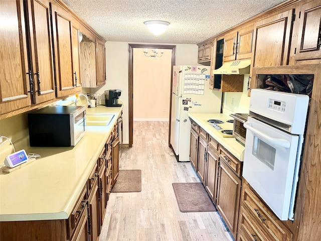 kitchen featuring a textured ceiling, white appliances, sink, light hardwood / wood-style flooring, and a chandelier