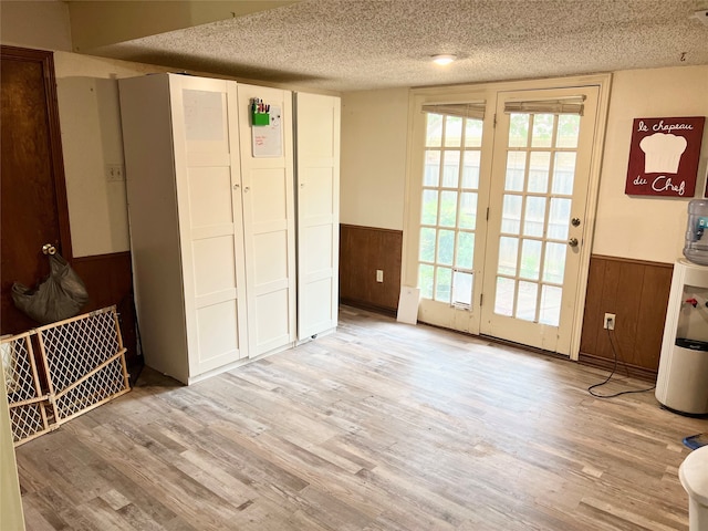 doorway with wood walls, light hardwood / wood-style flooring, and a textured ceiling