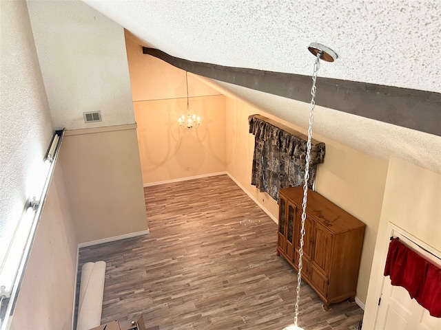 stairway with hardwood / wood-style floors, a notable chandelier, and a textured ceiling