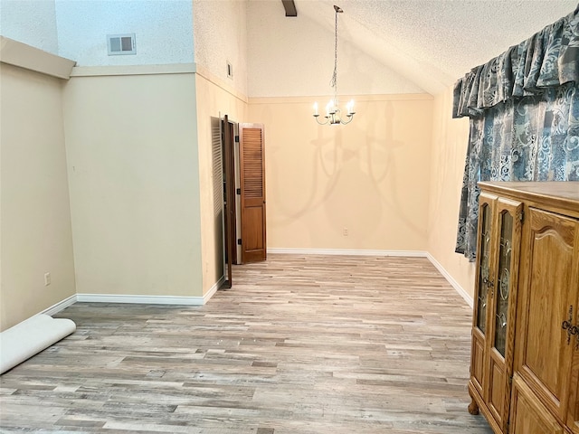 interior space featuring a textured ceiling, light hardwood / wood-style floors, high vaulted ceiling, and a notable chandelier