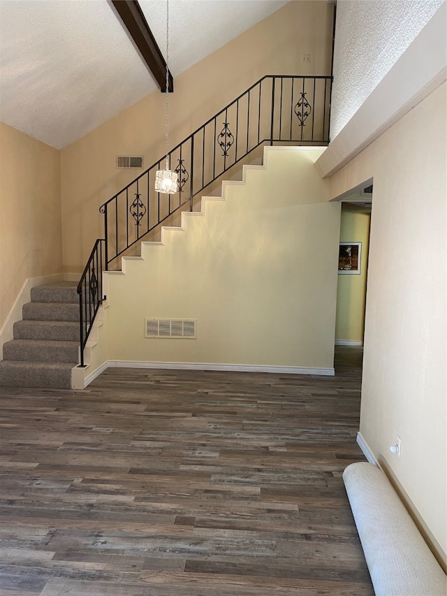 staircase featuring beam ceiling, high vaulted ceiling, a textured ceiling, and hardwood / wood-style flooring