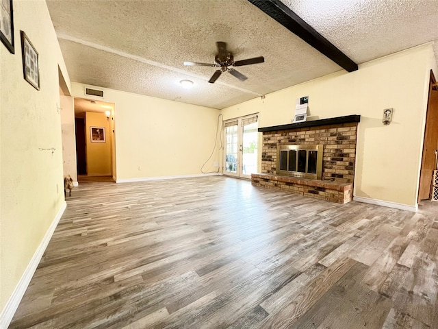 unfurnished living room featuring hardwood / wood-style floors, a textured ceiling, ceiling fan, and beam ceiling