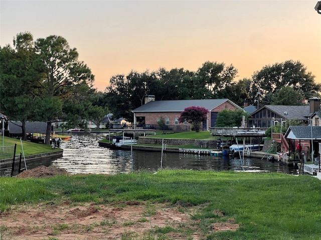 dock area with a water view and a lawn