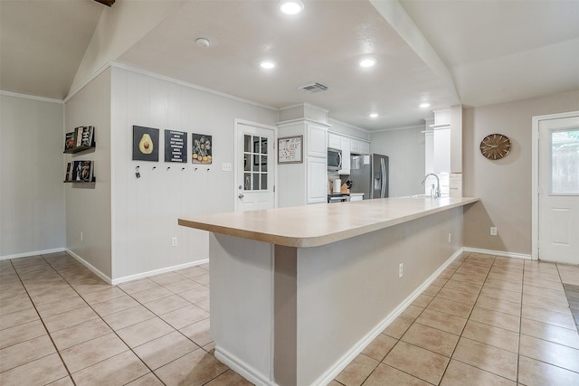 kitchen with appliances with stainless steel finishes, light tile patterned floors, white cabinets, and kitchen peninsula