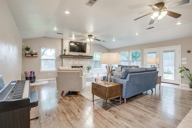 living room featuring lofted ceiling, a fireplace, plenty of natural light, and light hardwood / wood-style floors