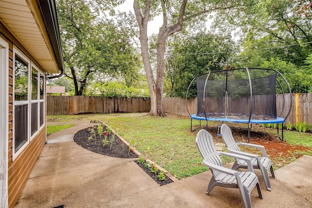 view of yard with a trampoline and a patio area