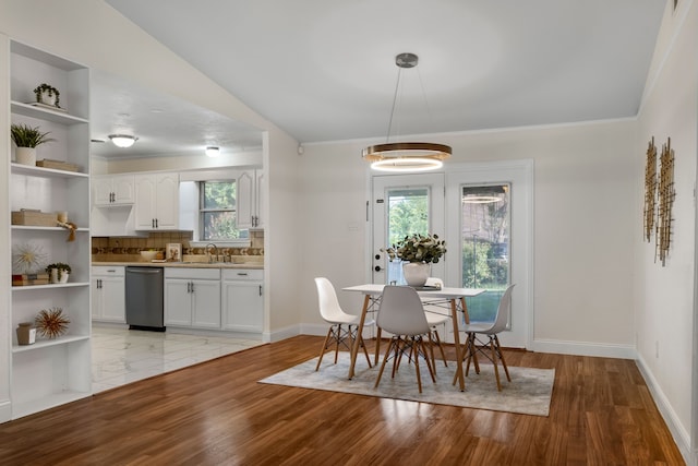 dining room featuring sink, vaulted ceiling, and light wood-type flooring