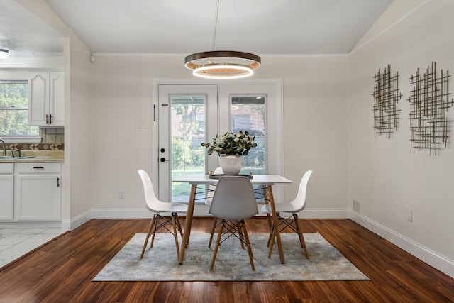 dining space featuring dark wood-type flooring, sink, and vaulted ceiling