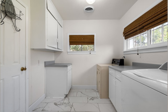 clothes washing area featuring cabinets and washing machine and clothes dryer