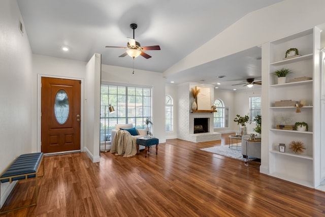 foyer entrance featuring a fireplace, hardwood / wood-style flooring, ceiling fan, and vaulted ceiling