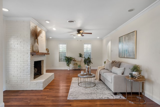 living room with ceiling fan, dark hardwood / wood-style floors, crown molding, and a brick fireplace