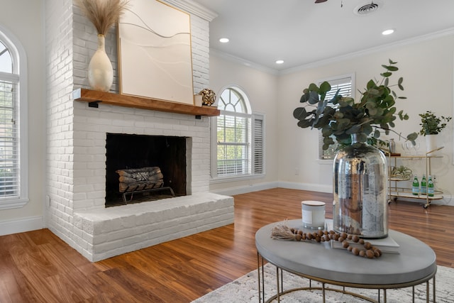 living room featuring ceiling fan, hardwood / wood-style floors, ornamental molding, and a fireplace