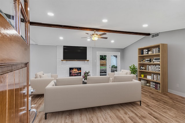 living room featuring ceiling fan, lofted ceiling with beams, a fireplace, and light hardwood / wood-style flooring