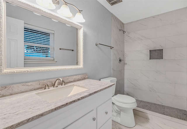 bathroom with toilet, vanity, and tiled shower