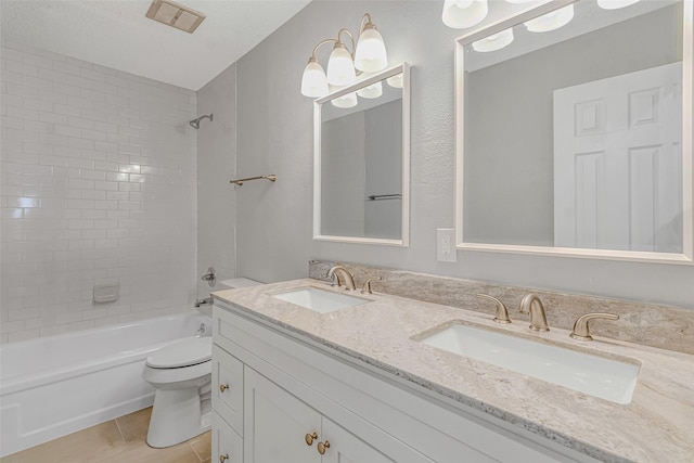 full bathroom featuring toilet, tiled shower / bath, vanity, tile patterned floors, and a textured ceiling