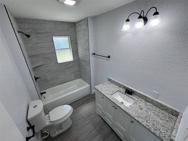 full bathroom featuring tiled shower / bath, a textured ceiling, toilet, vanity, and hardwood / wood-style flooring