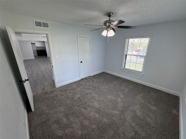 unfurnished bedroom featuring carpet flooring, a textured ceiling, a closet, and ceiling fan