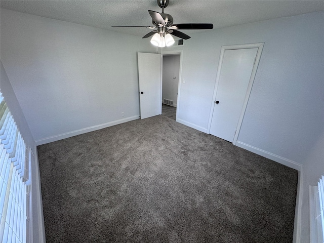 unfurnished bedroom with ceiling fan, a textured ceiling, and dark colored carpet