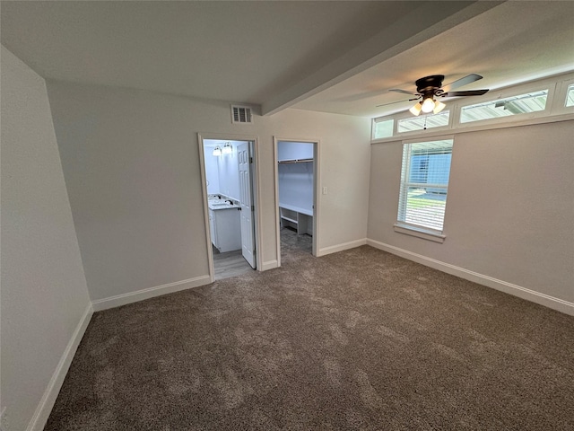 unfurnished bedroom with ceiling fan, carpet flooring, beam ceiling, and a spacious closet