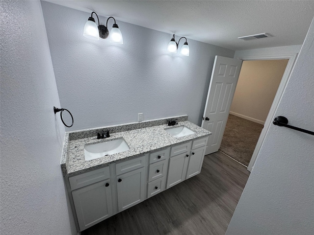 bathroom with wood-type flooring, vanity, and a textured ceiling