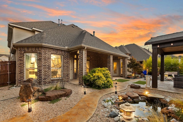 back house at dusk with a patio area