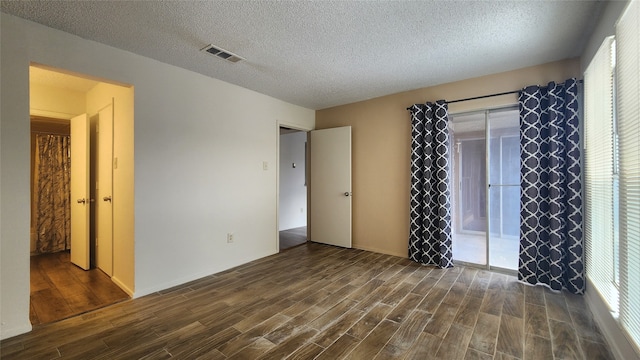 unfurnished bedroom with a textured ceiling and dark hardwood / wood-style floors