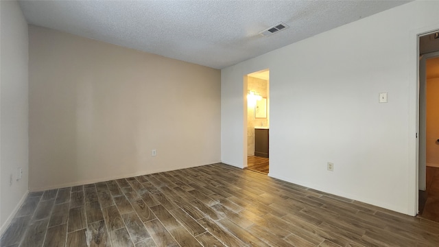 spare room featuring a textured ceiling and dark hardwood / wood-style floors