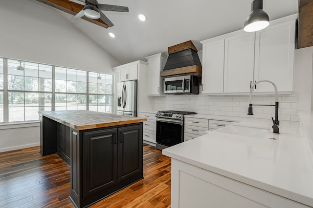 kitchen featuring appliances with stainless steel finishes, decorative backsplash, a center island, white cabinetry, and wood-type flooring