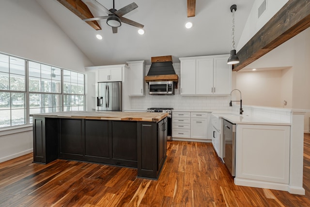 kitchen featuring backsplash, premium range hood, stainless steel appliances, beamed ceiling, and hardwood / wood-style floors