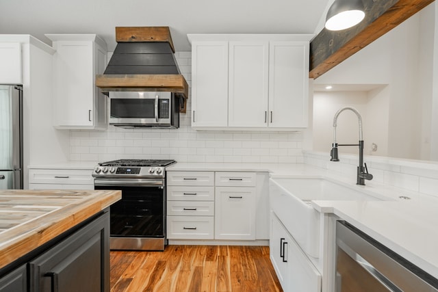 kitchen featuring appliances with stainless steel finishes, white cabinets, sink, backsplash, and light hardwood / wood-style floors