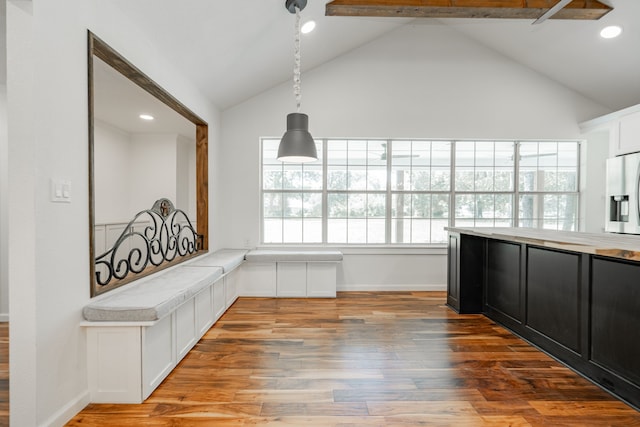 interior space featuring high vaulted ceiling, light hardwood / wood-style flooring, hanging light fixtures, and beam ceiling