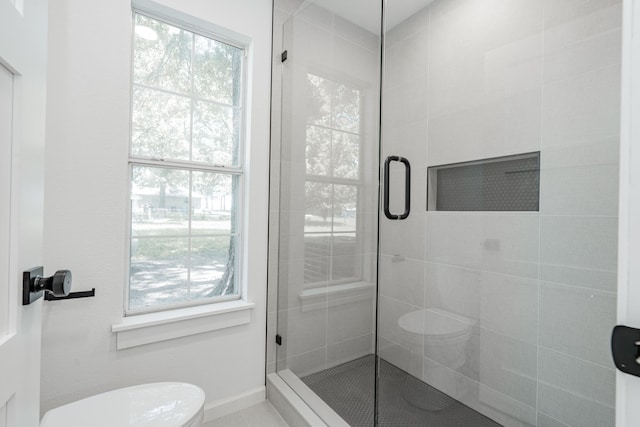 bathroom featuring a shower with door and toilet