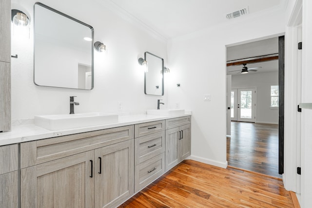 bathroom featuring hardwood / wood-style flooring, double sink vanity, ornamental molding, and ceiling fan