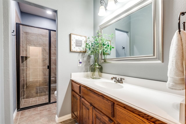 bathroom featuring toilet, a shower with shower door, tile patterned floors, and vanity