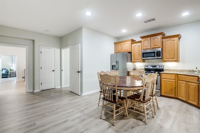 kitchen with light hardwood / wood-style floors, light stone countertops, and appliances with stainless steel finishes