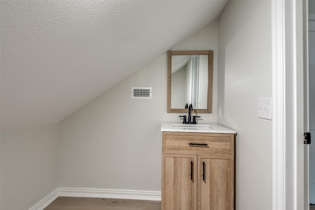 bathroom with wood-type flooring, vanity, and vaulted ceiling