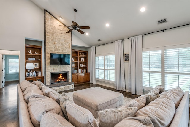 living room featuring built in shelves, ceiling fan, vaulted ceiling, and a stone fireplace